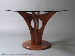 Circular designs accent the round drum table base. Modern Dining Table With Walnut Base And Round Glass Top