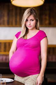 Pregnant woman in a red dress posing for a picture - SeaArt AI