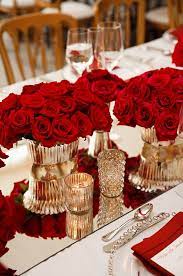 When we think of classic wedding flowers, there's one that's a clear stand out: Gorgeous Mirrored Table Runners Reflect Fresh Red Roses In Opulent Gold Containers Red Wedding Theme Wedding Decor Elegant Wedding Centerpieces