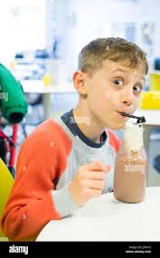 Seven year old boy drinking a chocolate milkshake, Kingsbridge, Devon,  England, United Kingdom Stock Photo