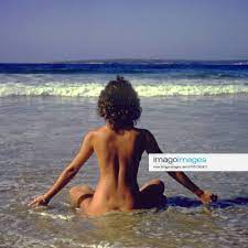 Junge Frau relaxt nackt am Strand
