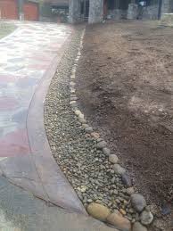Handling Rainwater Runoff From A Concrete Driveway With Beautiful River Gravel And River Rock Driveway Landscaping Landscaping With Rocks Backyard Landscaping