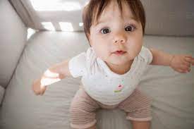 Baby Girl Sitting Up In Crib Stock Photo