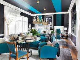 Exquisite tan and blue living room is furnished with facing tan striped sofas accented with blue pillows and positioned on either side of an iron and glass coffee table placed on a blue striped rug. Glamorous Living Room Mixes It Up Hgtv