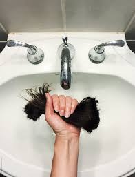 fist holding hunk of cut hair over sink