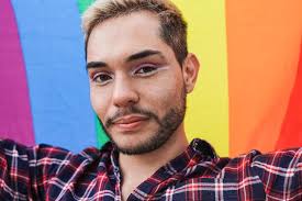 Premium Photo | Young gay man looking on camera while holding LGBT rainbwo  flag