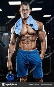 Handsome man with big muscles, posing at the camera in the gym — Stock  Photo © roman.l.olegovic 149560106