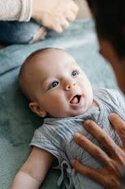 Baby With Surprise Face While Their Parents Are Playing With Him" by  Stocksy Contributor "Sergio Marcos"