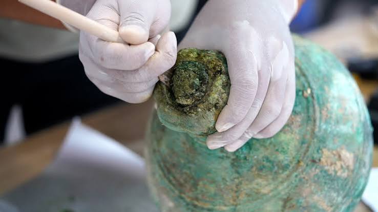 An ancient bronze vessel containing preserved liquid discovered within a tomb.