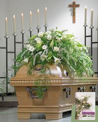 Uppig Thront Der Blutenschmuck Auf Dem Sarg Mit Lilien Gerbera Und Rispenspierenzweigen Neben Weiterem Grun Trauerfloristik Trauerschmuck Lilien