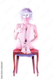 Eine nackte maskierte Frau sitzt mit angezogen Beinen auf einem Stuhl  Stock-Foto | Adobe Stock