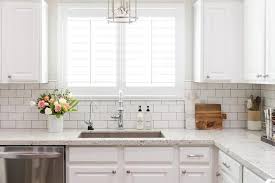 Window With White Frames Inside A Kitchen With A White Subway Tile Arrangement A In 2020 White Subway Tile Kitchen Kitchen Backsplash Designs White Granite Countertops