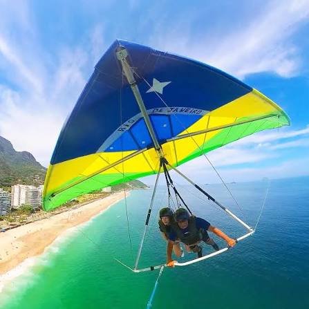 Uma foto mostrando os parapentes em São Conrado no fim de tarde