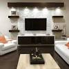 Styled white built in cabinets flank a barn board wall fitted with a flat panel television mounted above white tv cabinets. 1