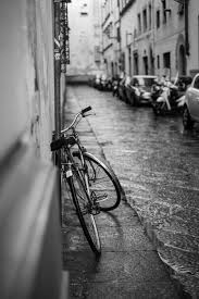 Black And White Shot Of Bike Leaning Against Wall In Street With Cars And Heavy Rain Street Photography Urban Street Photography Composition Photography