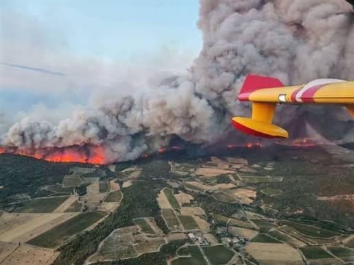 Aerial view of smoke plumes and charred landscapes across a rural French region during the summer wildfire crisis.