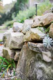 Using construction adhesive, secure your capstones and create the top layer of your retaining wall. How To Build A Boulder Retaining Wall How Tos Diy
