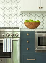 White And Blue Kitchen Boasts White Upper Cabinets And Dark Blue Lower Cabinets Adorned With Brass Hardwar Geometric Tile Backsplash Backsplash Tile Backsplash