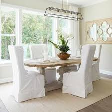 Oval Salvaged Wood Dining Table With White Slipcovered Wingback Dining Chairs Cottage Dining Rooms Dining Room Nook Reclaimed Wood Dining Table
