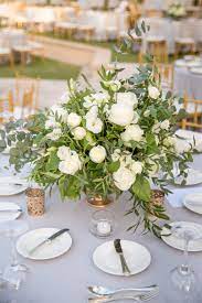 A textural greenery wedding centerpiece with various shades of green and dark green. White And Green Low Centerpiece Wedding Wedding Flower Table Decorations Green Wedding Centerpieces Wedding Table Flowers