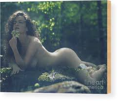 Beautiful nude woman lying naked in the forest with a wild flowe ...