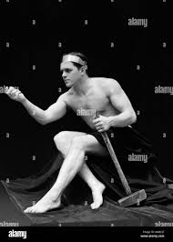 1920ER JAHRE MANN HALB NACKT KLASSISCHE POSE SITZEN HÄLT LANGE BEWAFFNETEN  HAMMER TRAGEN STIRNBAND RETRO VINTAGE Stockfotografie - Alamy