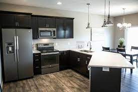 Minimalist black kitchen with modern cabinetry along with a black countertop and black appliances. Ge Black Slate Appliances Cabinet Stone