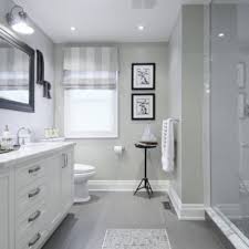 Elegant white and gray bathroom is lit by etoile sconces mounted on either side of a black oblong mirror hung from a wall clad in gray wallpaper over a white beadboard trim lined with a chair rail. 23 Ideas For Beautiful Gray Bathrooms