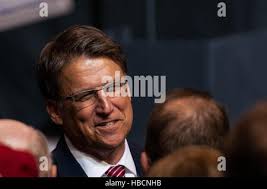 North Carolina Gov. Pat McCrory, left, and North Carolina head basketball  coach Roy Williams, right, watch David Love III tee off