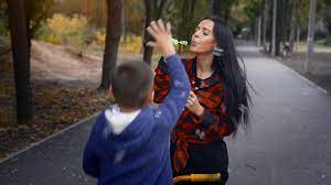 adult brunette mother blows a bubble with her son at the park at warm  autumn day 16159479 Stock Video at Vecteezy