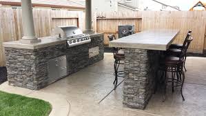A contemporary outdoor barbecue area done in black and stained wood, with matte cabinets, a grill, a hood and some meal spaces a contemporary outdoor barbecue area done in black and white, with a pizza oven and a grill plus storage cabinets Bbq Islands Sacramento What Is An Outdoor Bbq Island