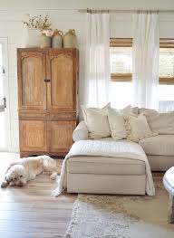 Taupe dining room features a french candle chandelier illuminating a wood dining table lined with a mix of restoration hardware klismos fabric side chairs and white wingback dining chairs beside an armoire with eclipse cabinet doors near the arched doorway and french paned floor mirror. Why Armoires Are Amazing Pieces Of Storage Furniture