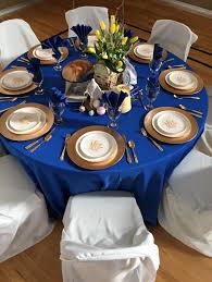 The dinner plate is in a bright gold, with a blue floral salad plate and a white napkin held together by a silver napkin ring. Relief Society March Birthday Celebration Royal Blue And Gold Wedding Blue Wedding Decorations Royal Blue Wedding Decorations