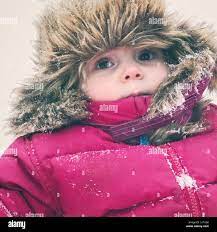 Baby Girl Bundled In Dark Pink Snowsuit And Faux Fur Trapper Hat Outside During A Heavy Snowfall In Canada Stock Photo Alamy