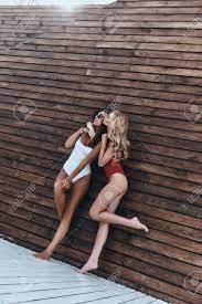 今まで親友!木製の壁屋外に対してポーズをしながら彼女の友人にキス水着で魅力的な若い女性の完全な長さの写真素材・画像素材 Image 88295130