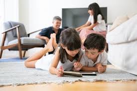 Sie sorgt für ein entspannendes ambiente im wohnzimmer. Nette Kleine Kinder Die Auf Boden Im Wohnzimmer Liegen Und Digitale Gerate Mit Lern Apps Verwenden Wahrend Eltern Lachen Kostenlose Foto