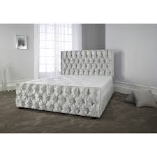 Upholstered in sleek microsuede, the headboard is highlighted with a row of decorative nail buttons outlining the silhouette. Crushed Velvet Furniture Crushed Velvet Sofas Beds Chairs Silver Grey Upholstered Bed Frame Luxury Bedding Master Bedroom Grey Bed Frame
