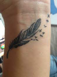 Color feather tattoo with flowers on the arm. Tattoo Feather And Birds Feather Tattoo Wrist Wrist Tattoos For Women Feminine Feather Tattoos