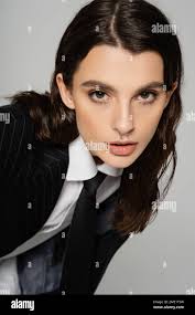 portrait of trendy brunette woman with makeup and piercing wearing formal  wear and looking at camera isolated on grey,stock image Stock Photo - Alamy