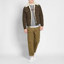 Crafted from a camel brown wool blend and cotton, this corduroy jacket features a faux fur lining, a button fastening, long sleeves and front flap pockets. Maison Kitsune Corduroy Trucker Jacket Khaki End