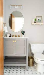 A white barn door on rails opens to an en suite bathroom boastin ga white curved bath vanity fixed beneath a round gold mirror. Light Gray Washstand With Pottery Barn Brass Faucet Transitional Bathroom