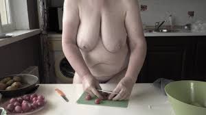 Голая зрелая толстушка-домохозяйка с большими обвисшими сиськами готовит на  кухне.