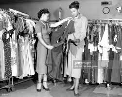 Salesgirl Mildred Graves of Blumstein's shows a dress to Wilma Greene. News  Photo
