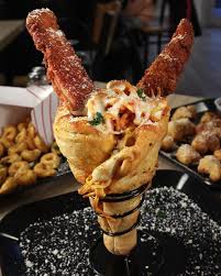 Handheld Chicken Parm Cone. Pasta, crispy chicken, and cheese in a cone  made of pizza dough. It's an Italian ice cream cone.