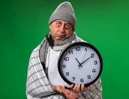 Free Photo Concerned Young Blonde Female Doctor Wearing Medical Robe And Stethoscope Around Neck Holding Clock From Behind It