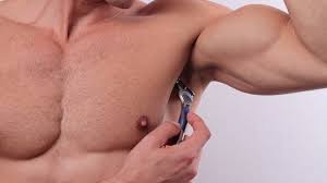 Young man using razor to remove hair from his armpit. P G Study Claims Blade Shaving Armpit Hair Could Reduce Male Body Odour