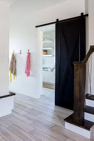Black And White Barn Door Wood Like Floor Tiles Lead To A Black Barn Door On Rails Opening To A White Laundry Room And Positi Interior Barn Doors White Laundry Rooms Modern Closet Doors