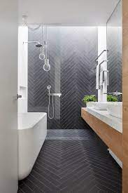 The dark tiles also draw your attention away from the walls on either side, so you don't feel as if you're in a corridor. Mark St Fitzroy North Ensuite Bathroom Chevron Tile Pattern Timber Joinery Marble Bencht Idee Salle De Bain Salle De Bains Carrelage Gris Salle De Bain 6m2