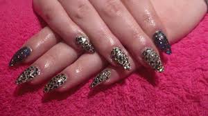 The accent nail is decorated with shiny rhinestones in silver and gold shades. Black And Gold Glitter With Leopard Print Acrylic Nails Acrylic Nails How To Nail Designs Youtube