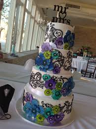 The design to the left is a three tier wedding cake with a fountain.the wire and royal spray on top adds even the water is colored blue, and flowers surround it. Elizabeth Ann Paisley Watercolor Daisy Wedding Cake In Blue Teal Lime Purple Pensacola Fl Lolo S Cakes Sweets